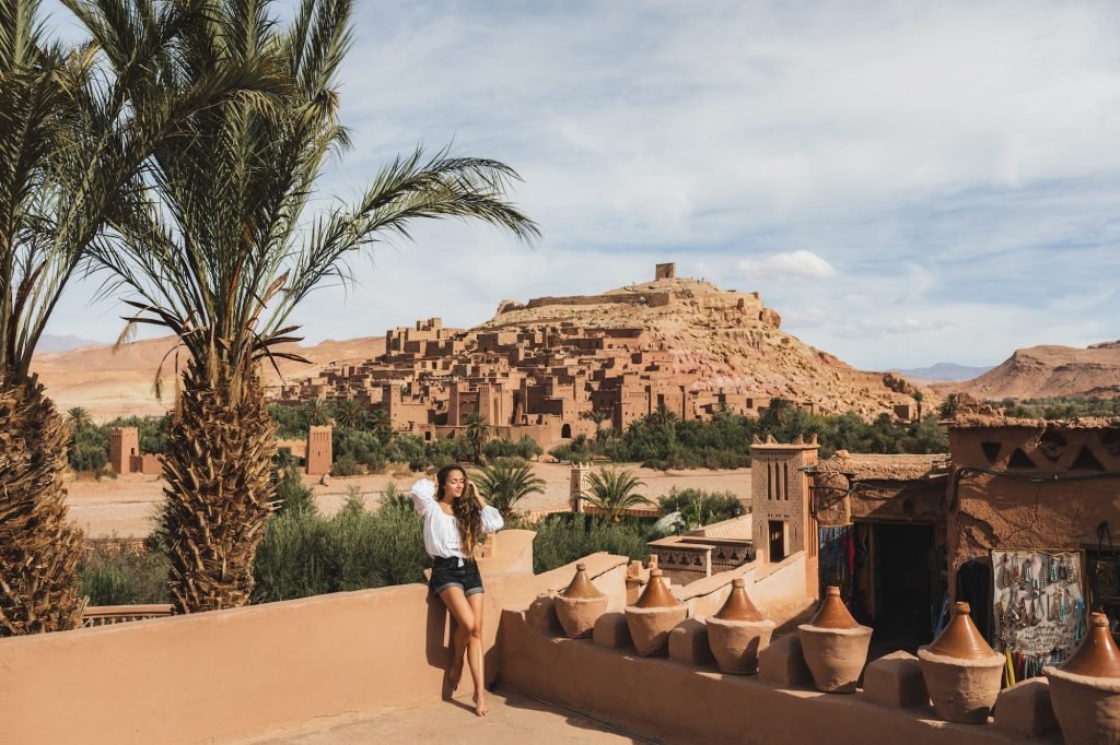 Beautiful young woman happy to travel in Morocco. Ait-Ben-Haddou kasbah on background