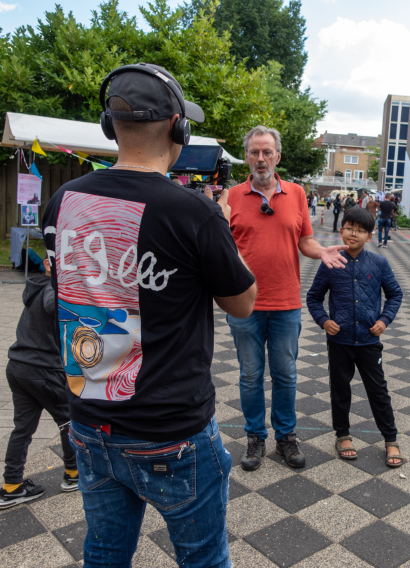 Close-up van een cameraman die met een professionele camera een interview opneemt, terwijl het gesprek zorgvuldig in beeld wordt gebracht.